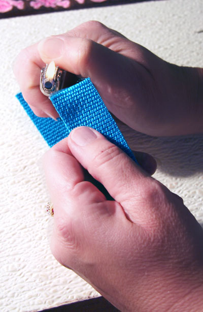 Edges of blue webbing being singed by a lighter