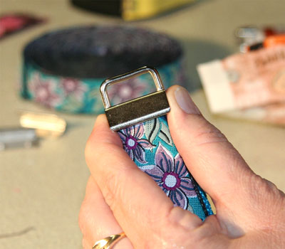 Blue floral webbing being fastened with metal clamp