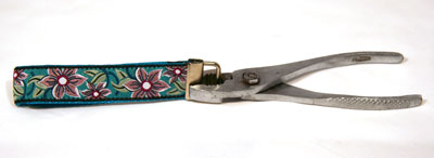 Metal clamp being pinched pinched onto blue floral material with pliers