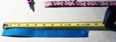Blue webbing being measured with a tape measure.