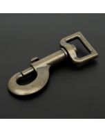 An antique brass snap hook on a black background