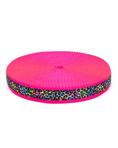 A roll of hot pink nylon webbing with grosgrain ribbon sewn onto it that has a gradient rainbow with leopard spots printed over it