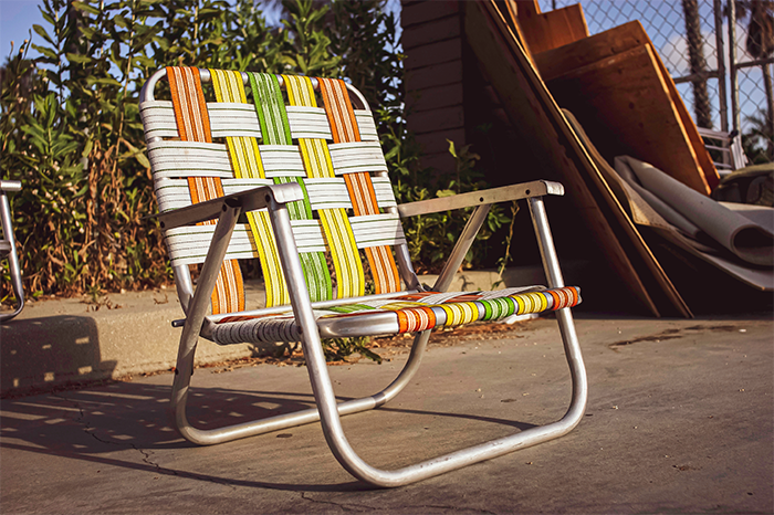 Repaired lawn chair from green, yellow, and orange polypropylene webbing