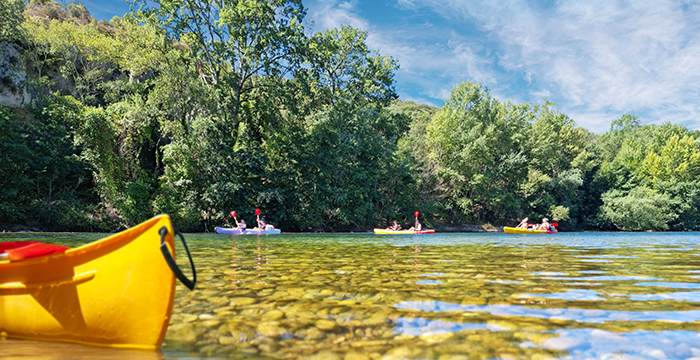 Yellow kayak in crystal clear water and other kayakers in the distance