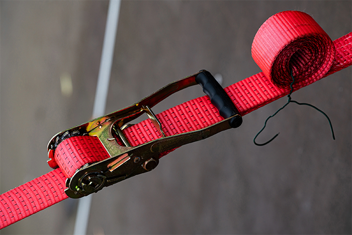 Red ratchet strap secured tightly for safe binding